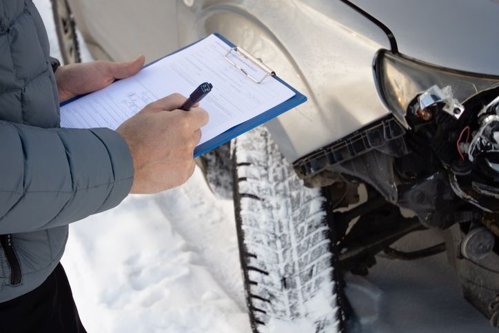 A person taking down notes during a snowy car accident